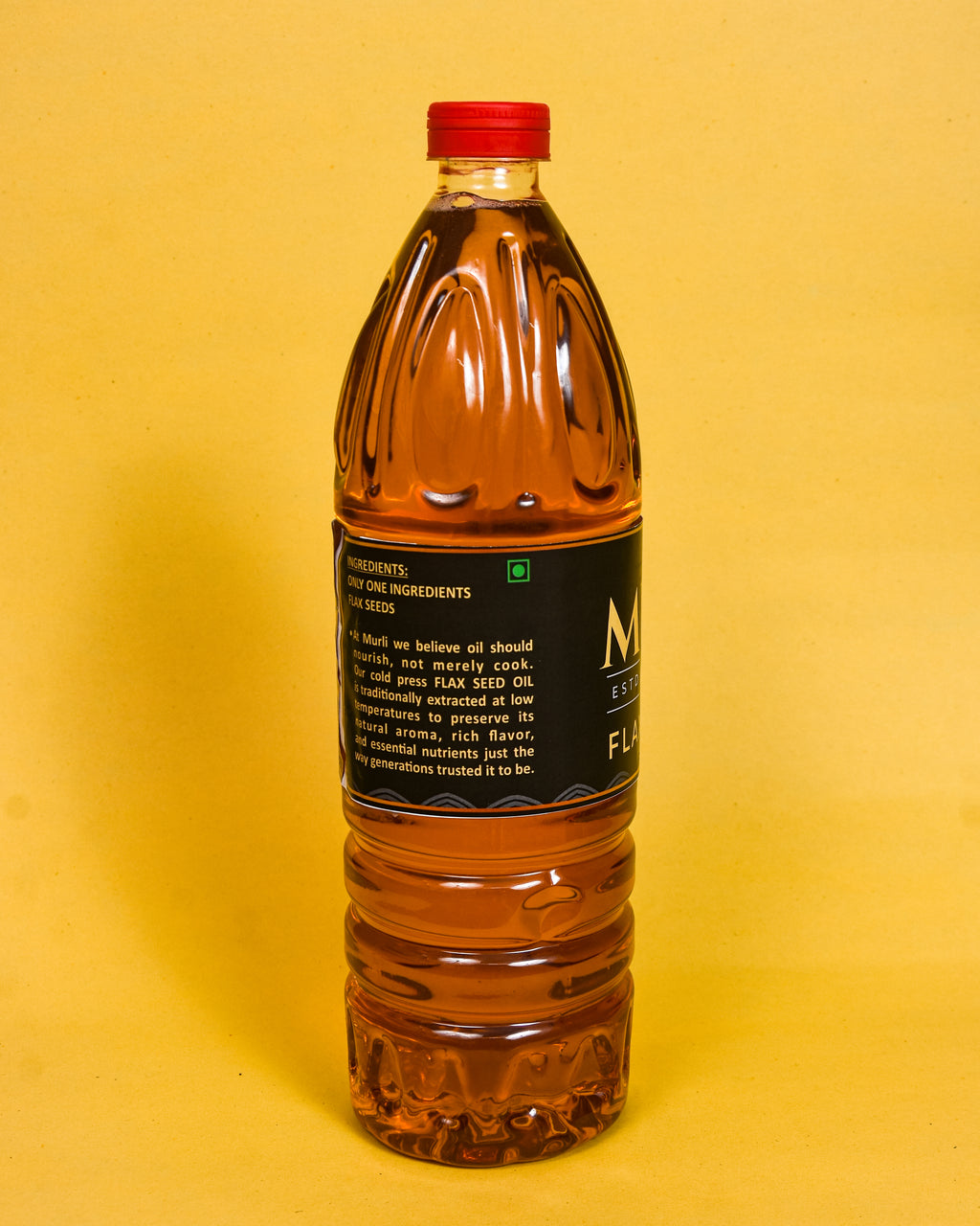 Cold pressed flax seed oil in clear bottle with red cap, golden liquid, black label, yellow background